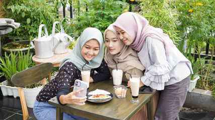 Asian hijab woman group selfie in cafe with friend