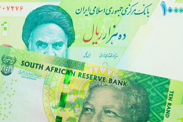 A macro image of a shiny, green 10 rand bill from South Africa paired up with a blue and green ten thousand rial bank note from Iran.  Shot close up in macro.