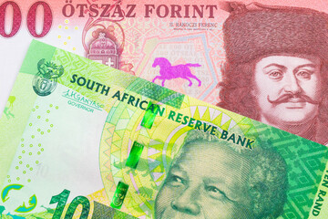A macro image of a shiny, green 10 rand bill from South Africa paired up with a red and white five hundred forint note from Hungary.  Shot close up in macro.