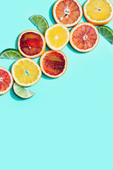 Composition with slices citrus fruits, grapefruit, red orange, lemon, lime on turquoise. Summer food flat lay with daylight.