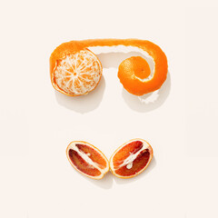 Summer fruits as face from tangerine and red orange. Creative citrus fruit food flat lay in minimal...
