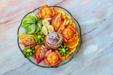 Sliced ​​fruits with powdered sugar on a plate. Fresh mix of fruits. Top view.