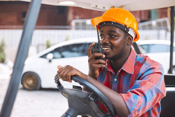 Afro loader worker is talking on the walkie-talkie in forklift.