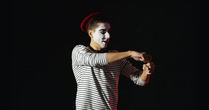 Miming male artist opening imaginary bottle of champagne on dark background