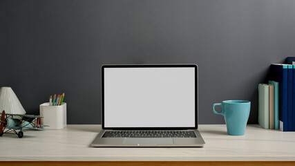 Worktable with laptop, stationery and decorations in home office room