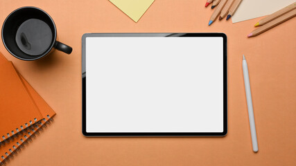 Top view of workspace with tablet, stationery and coffee mug on the table