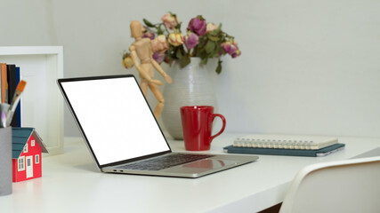 Side view of worktable with laptop, flower vase, supplies and decorations in home office