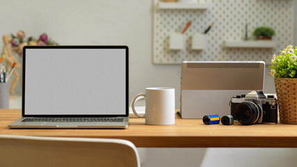 Cropped shot of office room with laptop, mug and camera on the table
