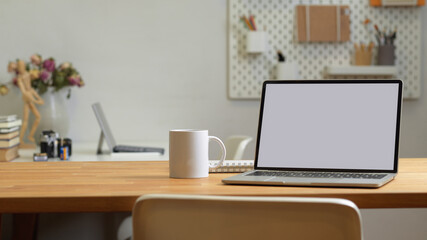 Close up view of office room with laptop, mug and copy space on the table