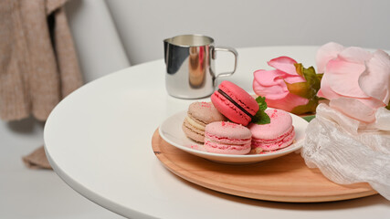 Coffee table with a plate of French colourful macarons decorated with roses flower