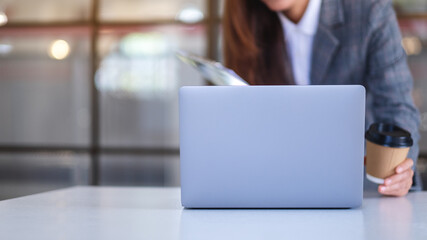 Closeup image of a business woman using laptop computer while working on paperwork in office