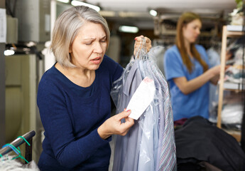 Mature woman complaining about cost of service at laundry