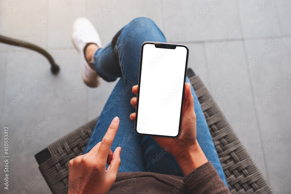 Poster top view mockup image of a woman holding mobile phone with blank white desktop screen