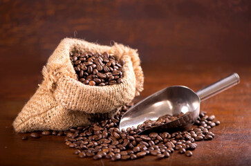 cup of coffee and coffee beans in a sack on dark background, top view