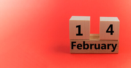 Wooden block calendar with the date February 14 on a red festive background with a copy of the space