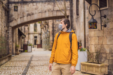 Young man wearing a medical mask during COVID-19 coronavirus tourist walks down the street in a European city after the end of COVID-19 coronavirus. quarantine