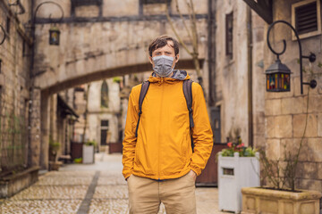 Fototapeta premium Young man wearing a medical mask during COVID-19 coronavirus tourist walks down the street in a European city after the end of COVID-19 coronavirus. quarantine