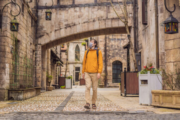 Young man wearing a medical mask during COVID-19 coronavirus tourist walks down the street in a European city after the end of COVID-19 coronavirus. quarantine