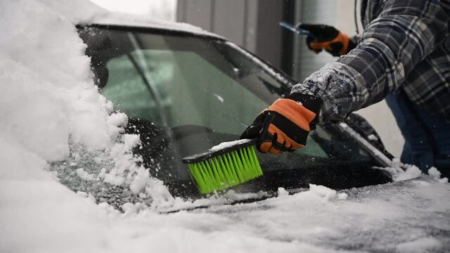 Men Removing Snow From His Vehicle and Deicing Windshield.