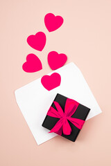 Gift box and paper envelope postcard and paper flying elements hearts cut. Pink heart and gift on pink background. Greeting gift card