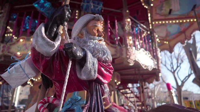 Christmas statue of Santa Claus on a merry-go-round, colourful carousel on a sunny day