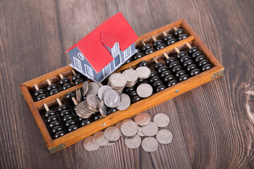 Chinese abacus, small house and scattered dollar coins