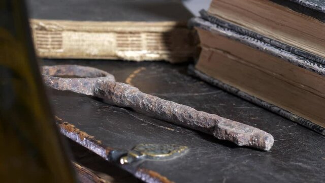 Close-up revealing pan of old rusty key by books on wooden table