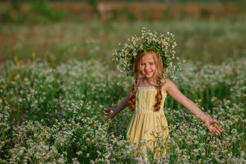 Fototapeta premium little girl in the field with a wreath on her head walking summer