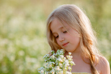 portrait of a little girl holding a bouquet in a field in summer