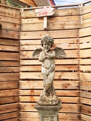 sculpture of an angel with wings in the park on the background of the wall.