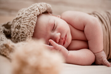 Newborn sleeping baby in knitted hat lies on the blanket .