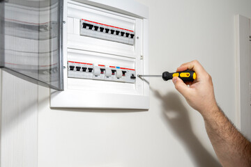 Electrician installing panel with electric meter in apartment of customer