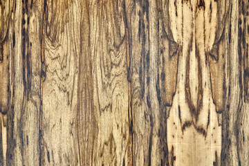 Texture of elegant contemporary Black Ofram natural veneer with abstract beige and brown patterns as background extreme closeup