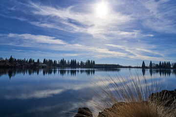 View of man made lake in Northern California with reflection of trees and clouds in water in Chico California 