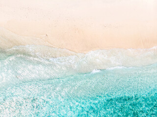 Aerial view of clear sea waves and white sandy beach in summer.