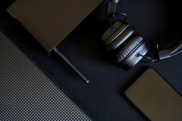 A black router and modern wireless gadgets - a smartphone and headphones lie on a dark background next to a gift box. Minimalistic black techno trend.