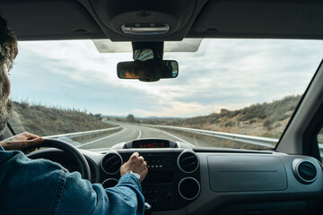 man driving a van from the rear view on the road.