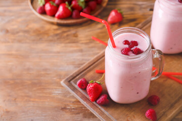 Mason jar of delicious smoothie with strawberry and raspberry on wooden background