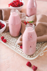 Bottles of smoothie with raspberry and cranberry on color background