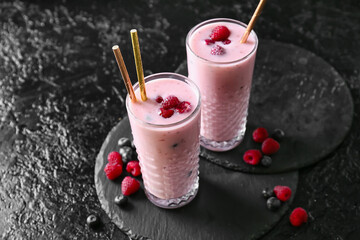 Glasses of delicious smoothie with blueberry and raspberry on dark background