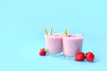 Glasses of tasty strawberry smoothie on color background
