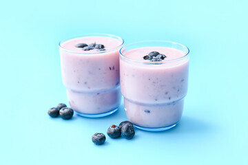 Glasses of tasty blueberry smoothie on color background