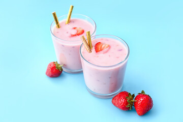 Glasses of tasty strawberry smoothie on color background
