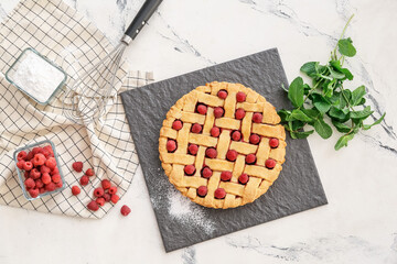 Tasty raspberry pie and ingredients on table