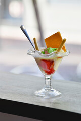 view of an ice cream with a spoon and an assortment of wafers on a table