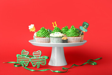 Stand with tasty cupcakes for St. Patrick's Day on color background