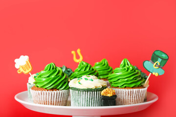 Stand with tasty cupcakes for St. Patrick's Day on color background