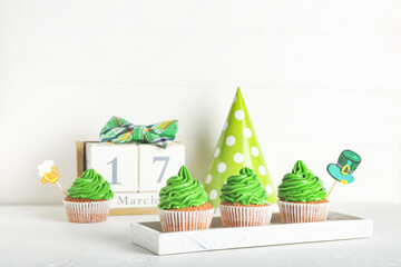 Tasty cupcakes for St. Patrick's Day and calendar on white background