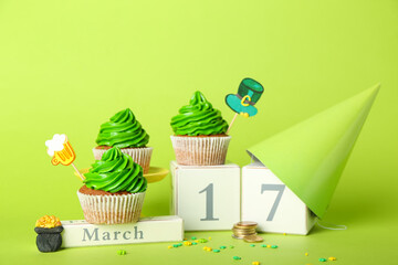 Composition with tasty cupcakes for St. Patrick's Day and calendar on color background