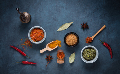 Various bowls and spoons of turkish spices on  dark blue background